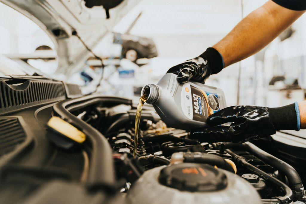 pexels-photo-13065690-13065690 Close-up of a mechanic pouring engine oil into a car engine in an auto repair shop.