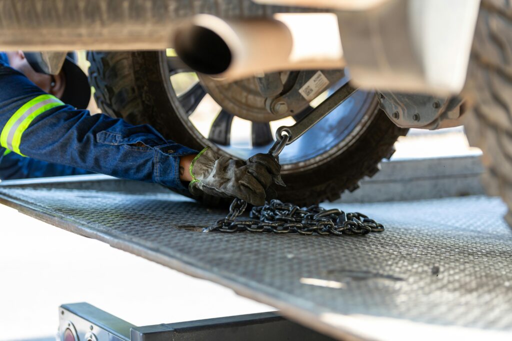 pexels-photo-17429095-17429095 Mechanic securing a vehicle on a service platform with a chain for safe towing.
